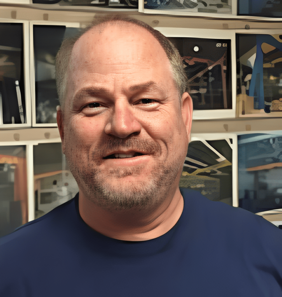 Man smiling in front of wall photos