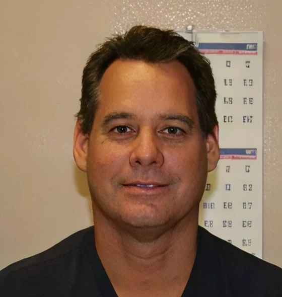 Man smiling in front of eye chart